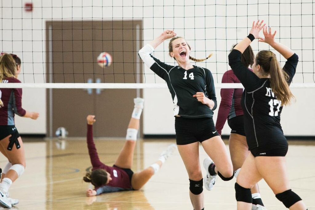 A girls volleyball team celebrating after scoring a point
